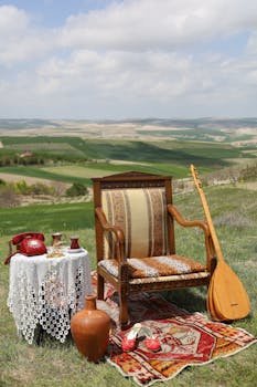 A cozy outdoor tea setting with a vintage chair, table, and traditional decorations on a scenic hillside.